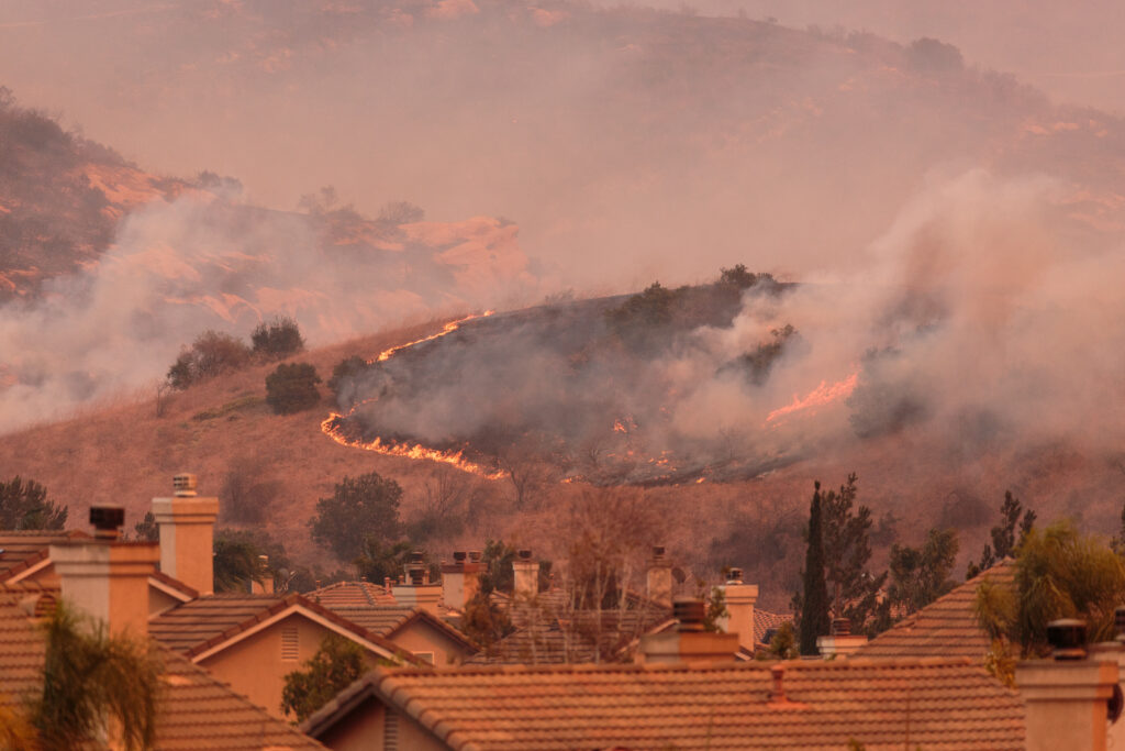 a wildfire burning behind a neighborhood