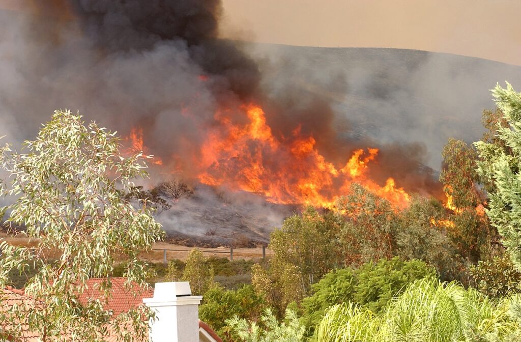 a wildfire burning on a hill behind houses