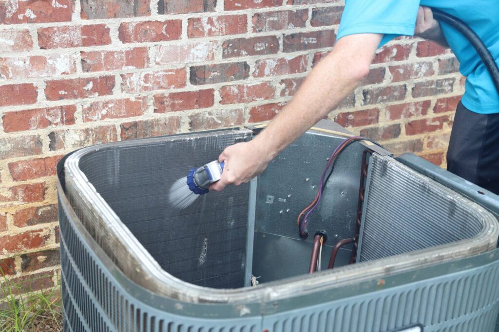 A homeowner cleaning an HVAC coils