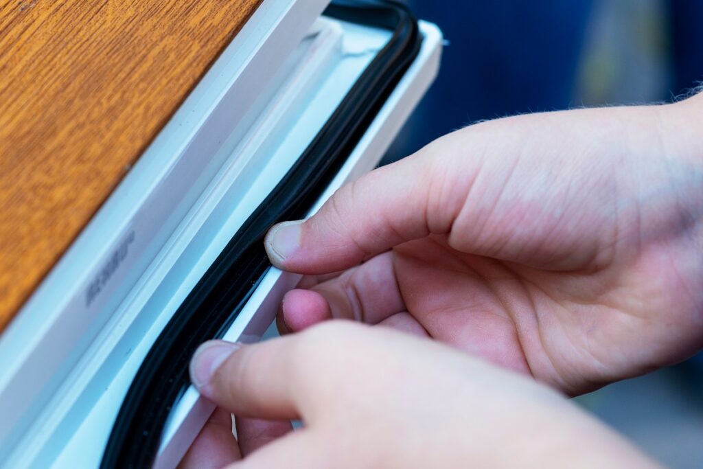 A homeowner applying weather stripping to their windows