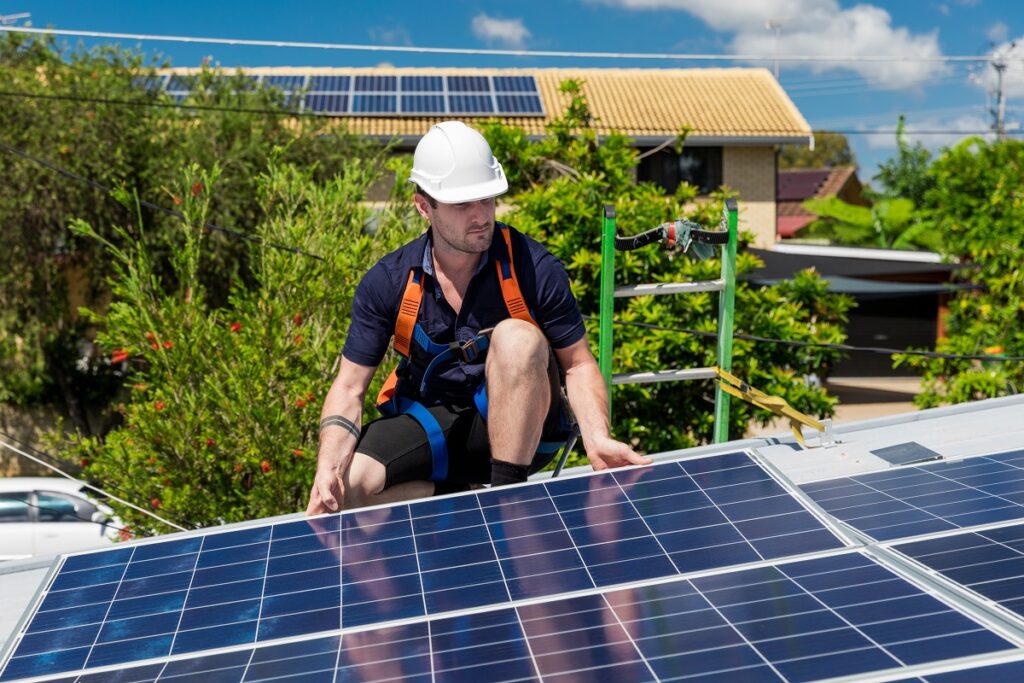 an installer placing a solar panel on a roof